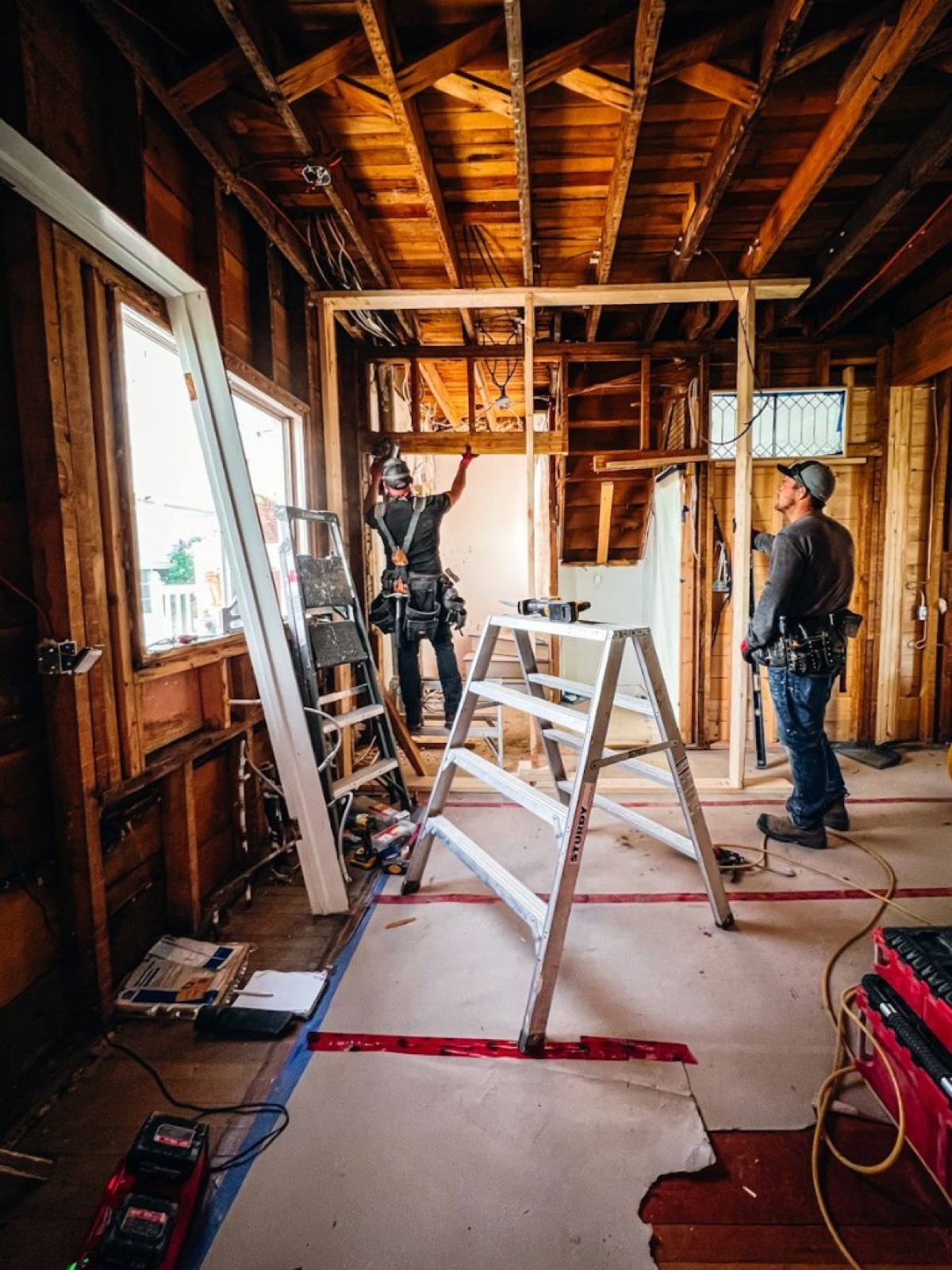 Crew in a gutted room, exposed framing